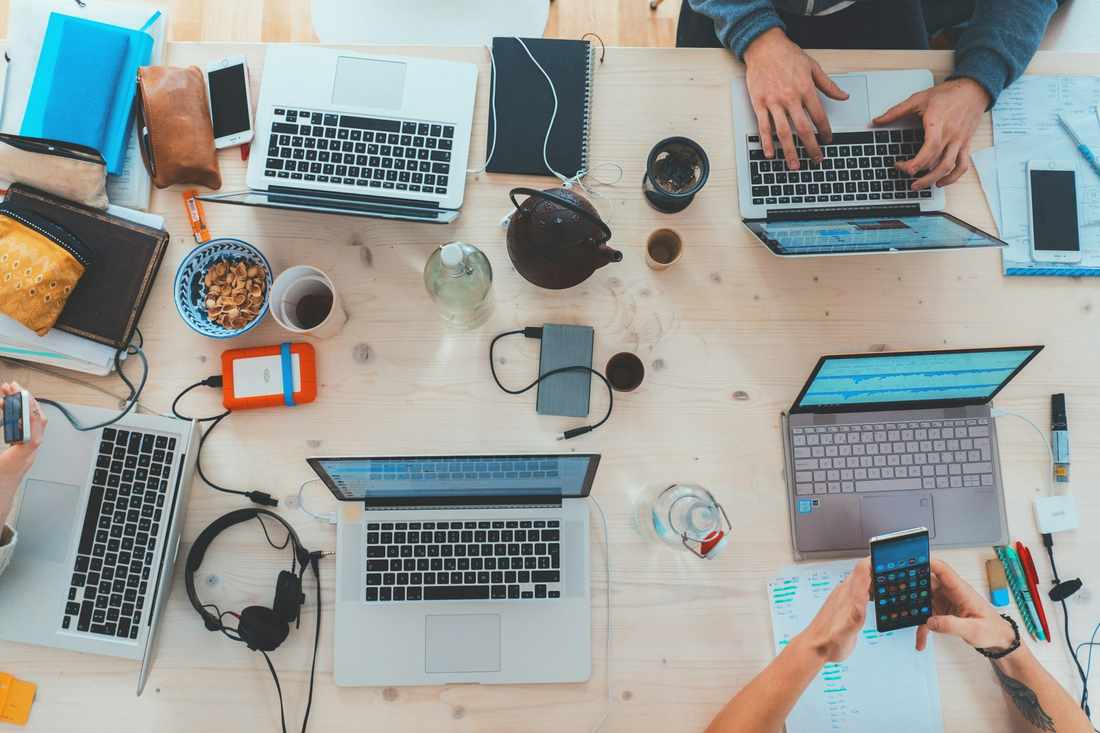 Shared desk with laptops and notebooks